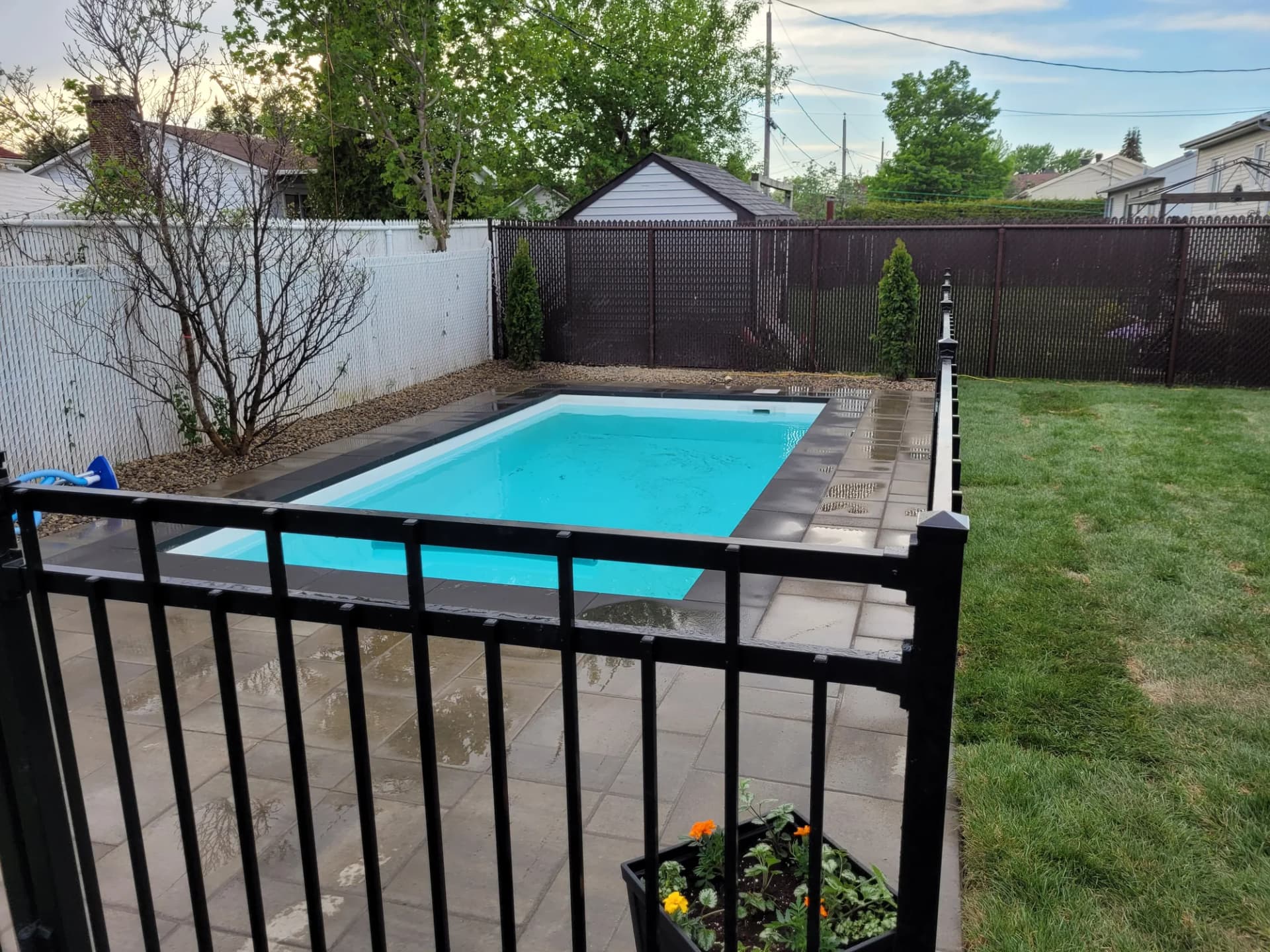 Piscine creusée avec contour en dalles et clôture de sécurité en aluminium noir