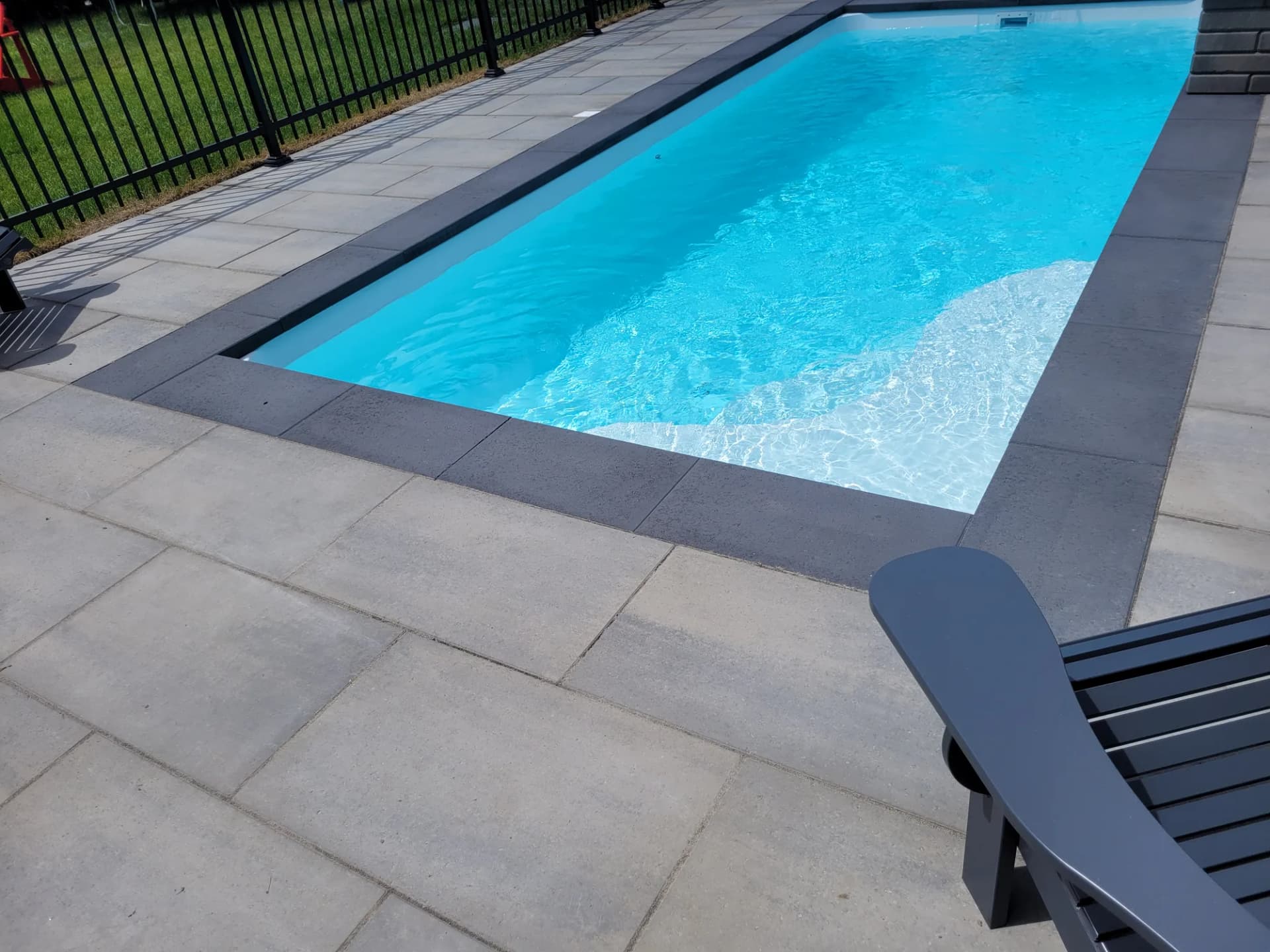 Contour de piscine en dalles grises avec bordure foncée sur la Rive-Sud
