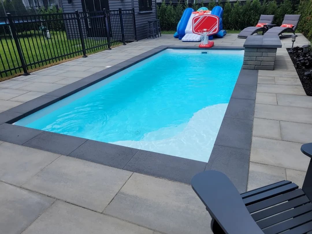 Piscine creusée avec contour en dalles grand format et bordure de margelle foncée