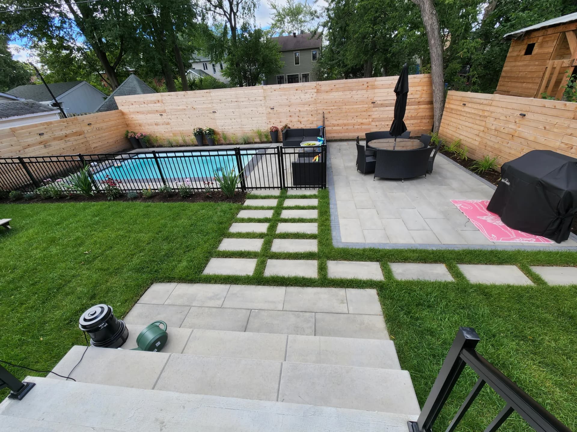 Cour arrière complète avec terrasse en dalles, pas japonais, gazon et piscine clôturée
