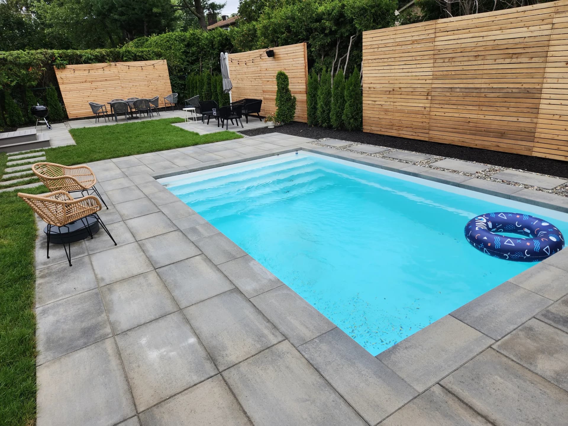 Piscine creusée avec contour en dalles grand format et écrans en cèdre sur la Rive-Sud