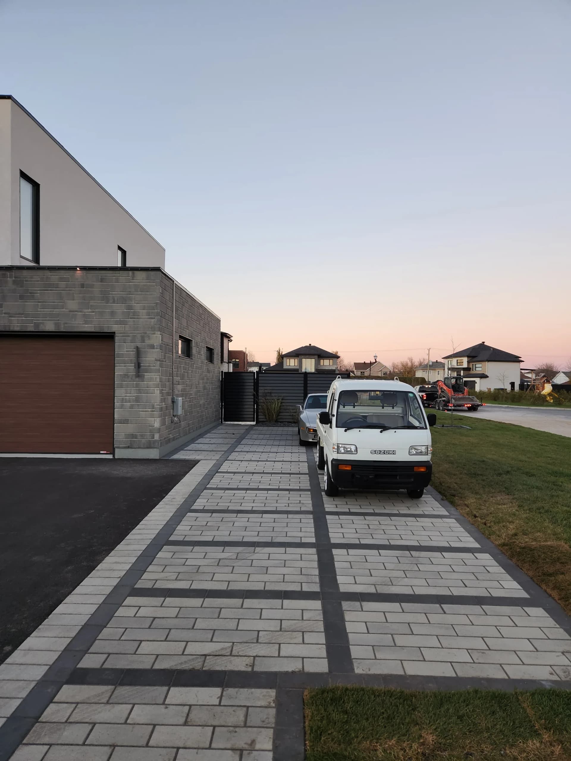 Allée d'entrée en pavé à motif de bandes foncées devant une maison contemporaine
