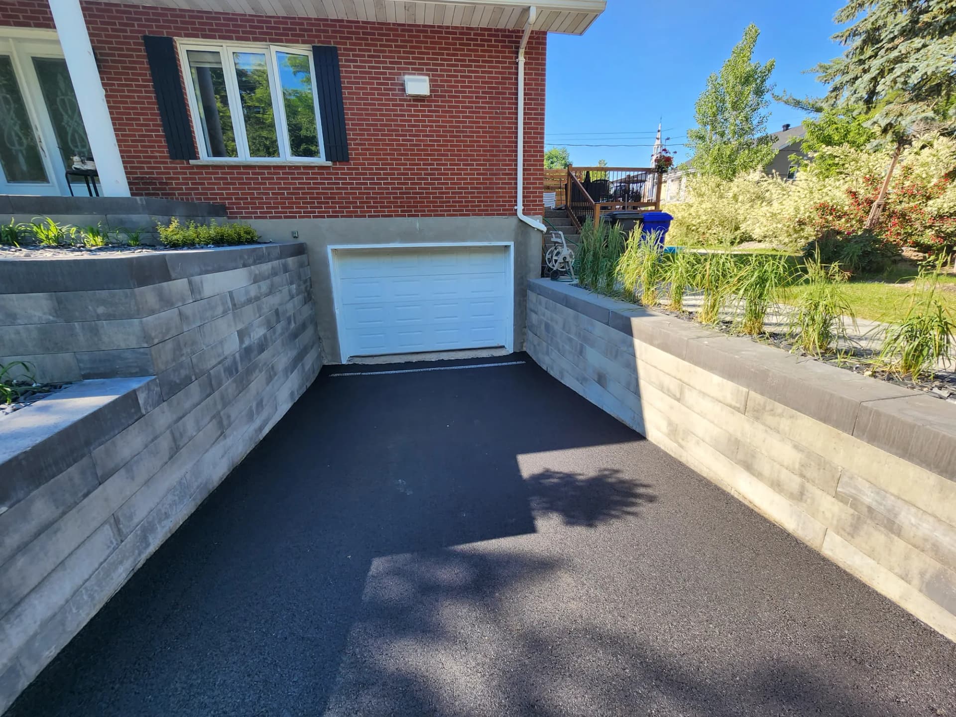 Murets de soutènement en blocs de béton encadrant une descente de garage