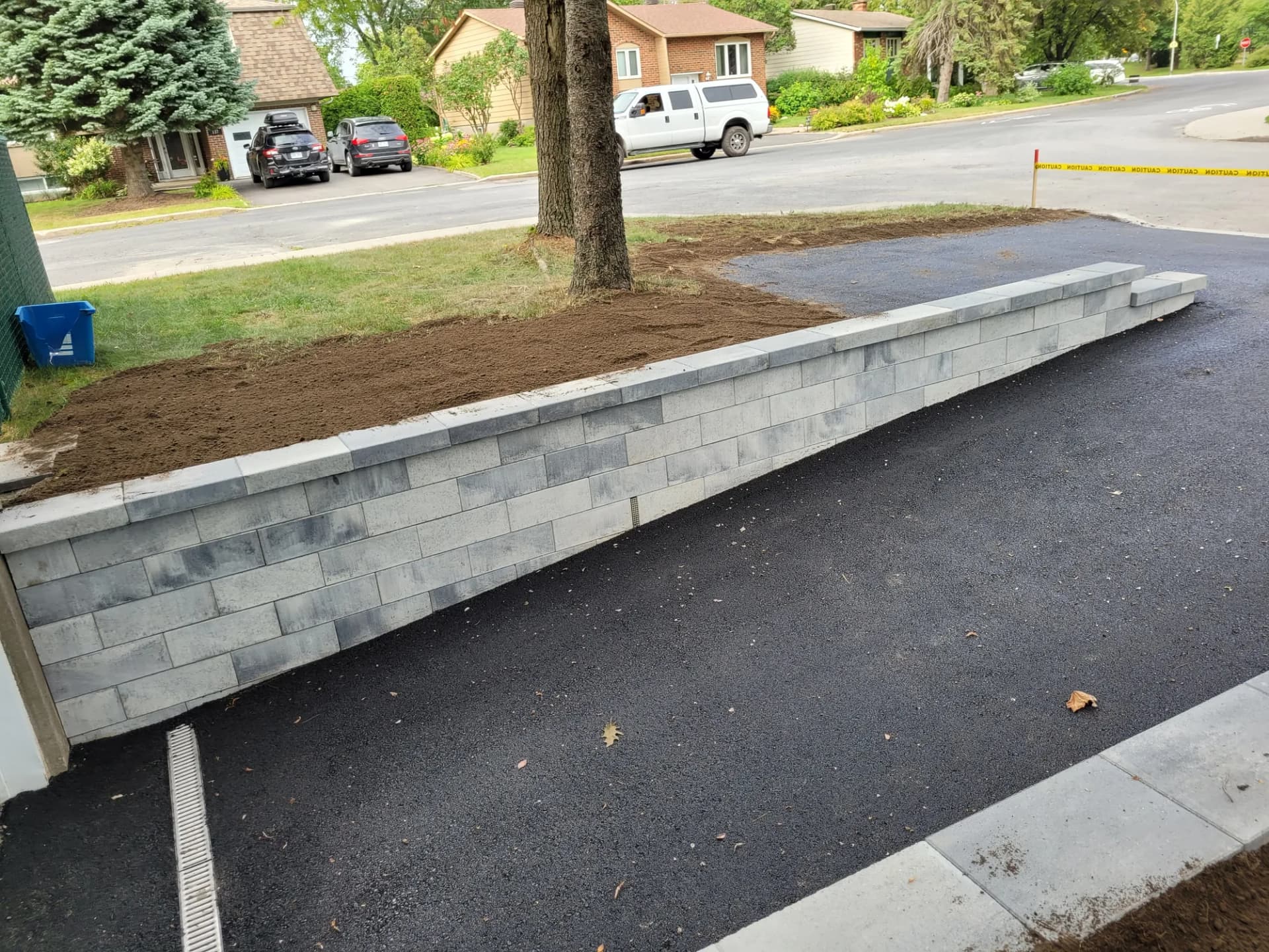 Muret de soutènement en blocs de béton le long d'une entrée asphaltée