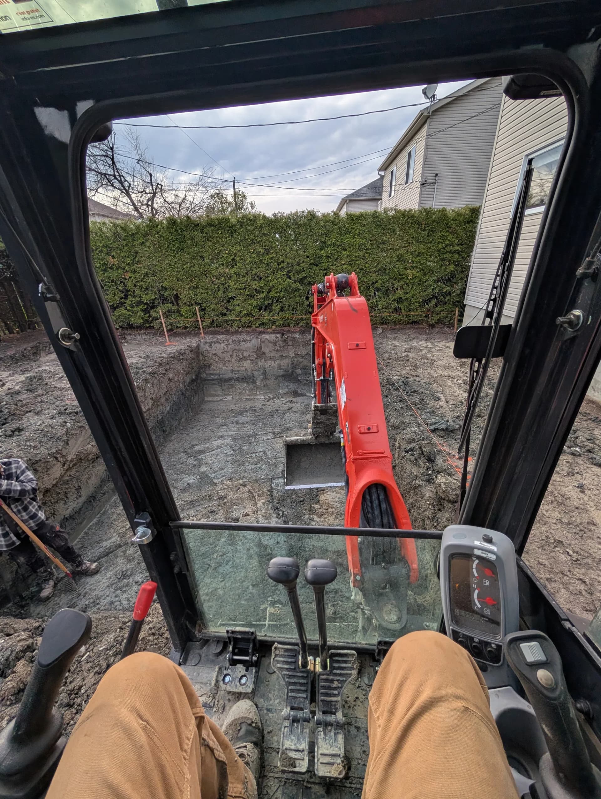 Vue depuis la cabine d'une mini-pelle pendant l'excavation d'une piscine