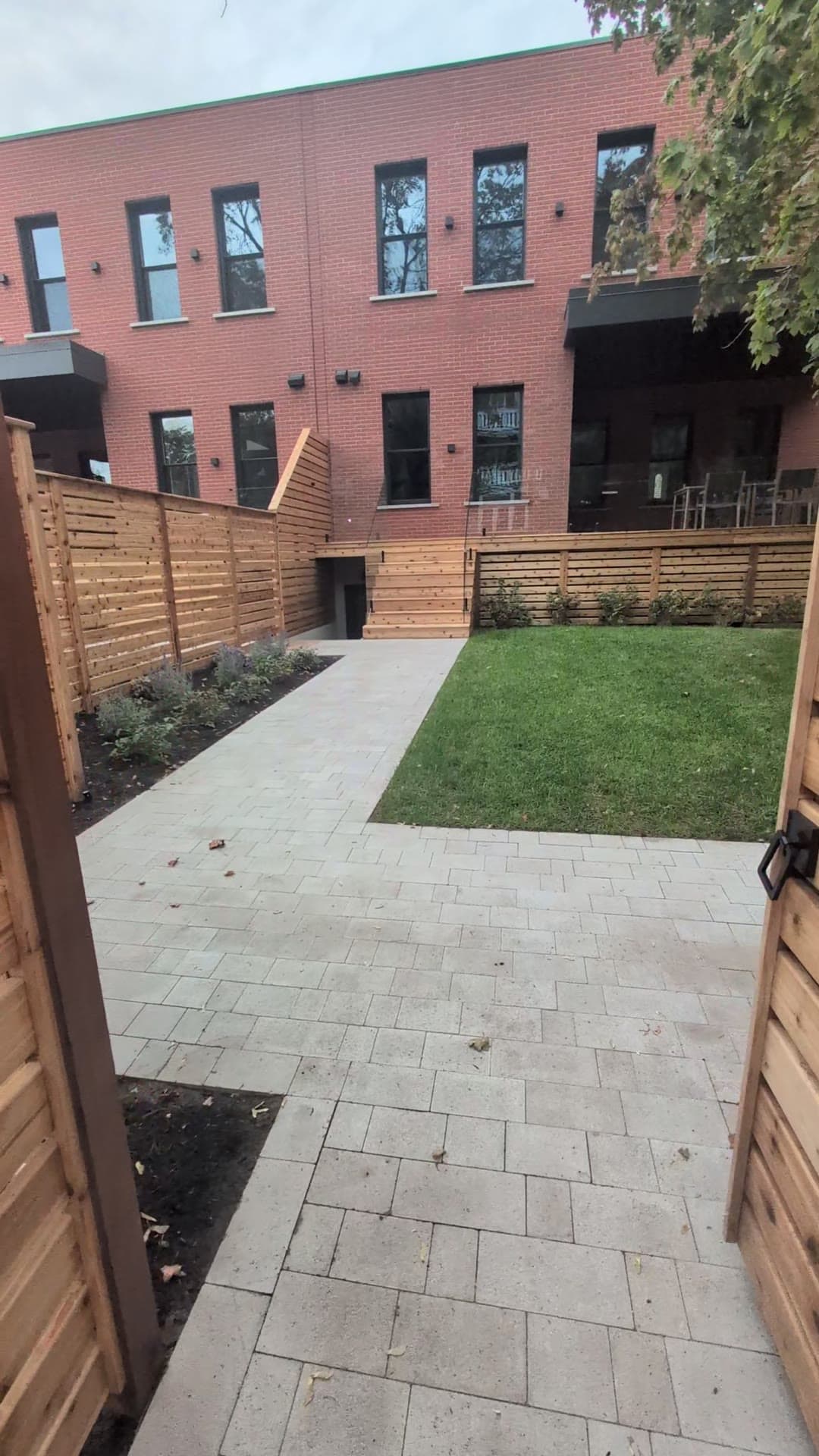 Cour arrière urbaine avec allée en pavé, deck en cèdre et clôture horizontale