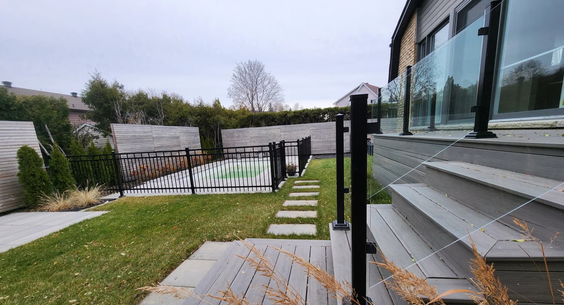 Terrasse en composite avec garde-corps en verre et allée en dalles, cour arrière Rive-Sud