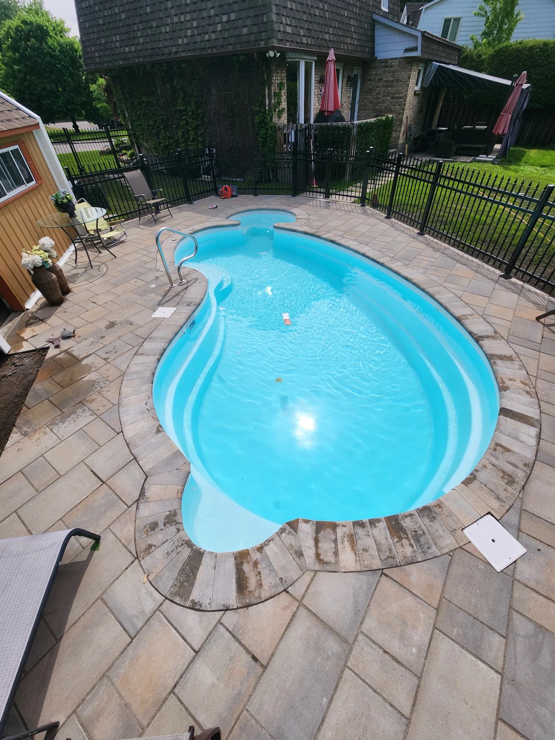 Piscine creusée en fibre de verre avec contour en pavé, aménagement Rive-Sud de Montréal